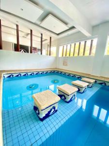 una gran piscina con 4 sillas. en Hotel Lu Acapulco en Acapulco