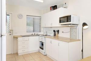 a kitchen with white cabinets and a microwave at Ocean Sands 1 in Sawtell