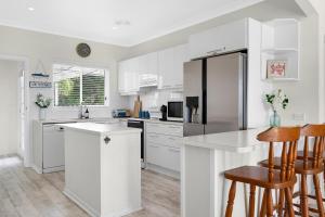 cocina blanca con armarios blancos y nevera en AXL Orion Beach Home: Beach front, en Vincentia