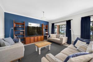 a living room with two couches and a tv at AXL Orion Beach Home: Beach front in Vincentia