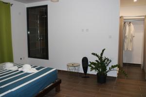 - une chambre avec un lit et une plante en pot dans l'établissement Villa Perle - 2 suites, à Matoury