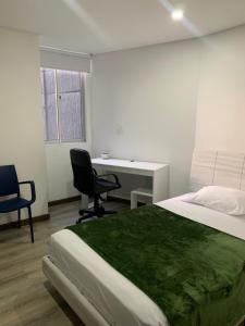 a bedroom with a bed and a desk and two chairs at Fabuloso apartamento in Armenia