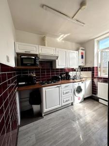 a kitchen with white cabinets and a washer and dryer at Stunning 2-bed apt near central London. in London