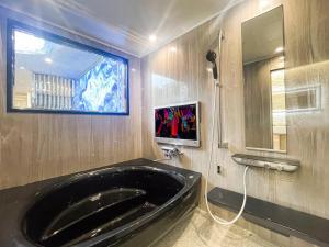eine große schwarze Badewanne im Bad mit Fenster in der Unterkunft Hotel QUEEN ANNEX in Tokio