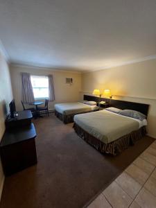 a hotel room with two beds and a table at Hotel Victoria in Lillooet