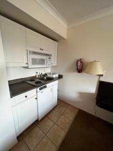 a kitchen with white cabinets and a sink and a microwave at Hotel Victoria in Lillooet