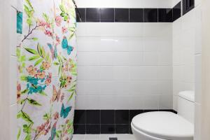 a bathroom with a toilet and a shower curtain with butterflies at District Inn in Manila