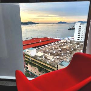 a red chair in front of a window with a view of the ocean at THE SHORE KOTA KINABALU - SABAKUBA HOMESTAY B13-13A in Kota Kinabalu