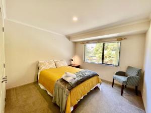 a bedroom with a bed and a window and a chair at Abeam of Reserve Living in Rotorua