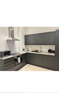 a kitchen with black and white cabinets and appliances at Modern 2bed Sutton in Sutton