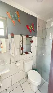 La salle de bains est pourvue de toilettes et de papillons sur le mur. dans l'établissement Casa Aconchegante Em Paraty, à Parati