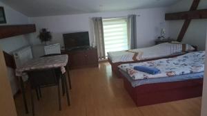 a bedroom with two beds and a table and a television at Pensjonat Stary Mlyn Tuczno in Tuczno