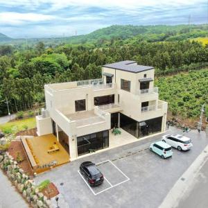 una casa grande con dos coches aparcados en un estacionamiento en Jeju Bomewasan en Jeju