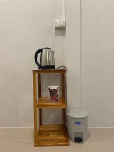 a small wooden shelf with a tea kettle and a trash can at Phu Thai Resort in Sukhothai