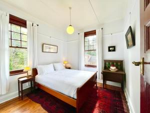 - une chambre avec un lit et 2 fenêtres dans l'établissement Violet's Maison, à Katoomba