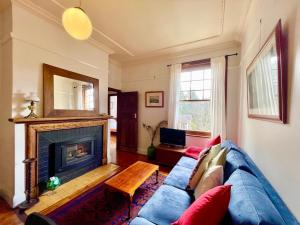 sala de estar con sofá azul y chimenea en Violet's Maison en Katoomba