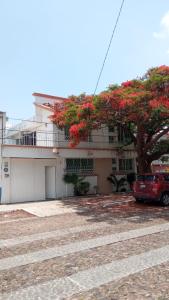 um carro estacionado em frente a um edifício com uma árvore em Casa Flamboyant em Querétaro