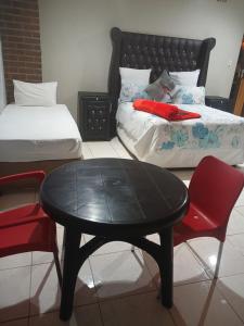 a black table and chair in a room with two beds at 26 Zea avenue Arcon Park Guest House in Vereeniging