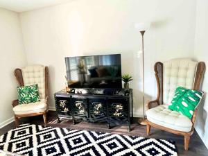 The Green Tee Suite في بينهورست: غرفة معيشة مع كرسيين وتلفزيون بشاشة مسطحة