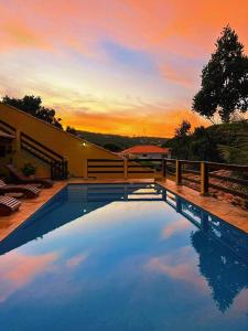 una piscina con puesta de sol en el fondo en Meu Cantinho Familiar en Búzios