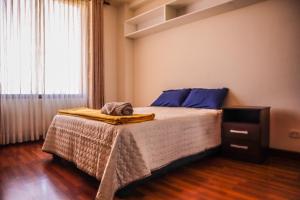 ein Schlafzimmer mit einem Bett mit blauen Kissen und einem Fenster in der Unterkunft Amplio Departamento en la mejor zona de Cochabamba in Cochabamba