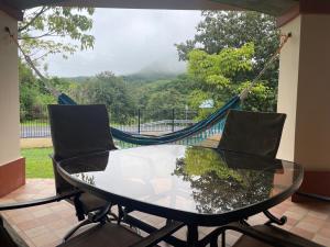 een glazen tafel en 2 stoelen op een veranda met een hangmat bij Boca De Los Rios River Site in Penonomé