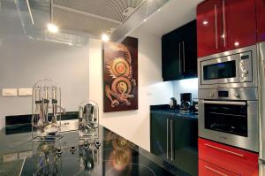 a kitchen with black counter tops and red cabinets at Absolute Bangla Suites in Patong Beach