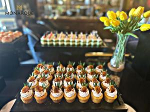 a bunch of cupcakes on a table with flowers at Monarque Hotel Danang in Da Nang