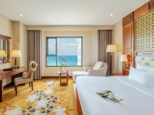 a hotel room with a bed and a view of the ocean at DLG Hotel Danang in Da Nang
