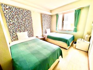 ein Hotelzimmer mit 2 Betten und einem Fenster in der Unterkunft Hotel Happy Holiday Ishigaki in Ishigaki-jima