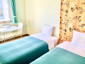 two beds in a room with a table and a desk at Hotel Happy Holiday Ishigaki in Ishigaki Island