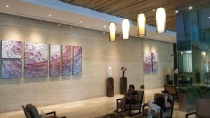 two people sitting in chairs in a lobby with paintings on the wall at MCity Jalan Ampang in Kuala Lumpur