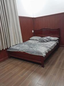 uma cama num quarto com piso em madeira em Phụng Kim Thảo Hotel Long An em Long An
