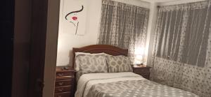 a bedroom with a bed and a window with curtains at Departamento Emily in Cuenca