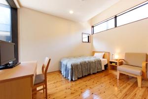 Schlafzimmer mit einem Bett, einem Schreibtisch und einem TV in der Unterkunft Yamashitako Lodge in Yufu