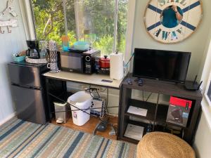 a kitchen with a desk with a microwave and a television at Cozy jungle boat hideaway with stunning ocean view in Kealakekua
