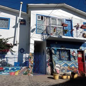 une maison blanche avec une fresque murale sur son côté dans l'établissement Hostal Destino Bellavista, à Valparaíso