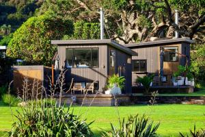 a tiny house with a porch and a deck at Adventurer's Chest - Pohutukawa in Hotwater Beach