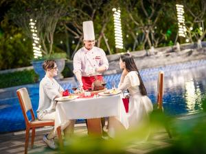 a man in a chefs hat standing next to a table at DLG Hotel Danang in Da Nang