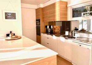 a kitchen with white counters and wooden cabinets at The Sandbar House, Royal National Park, waterfront beach house in Maianbar