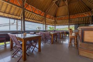 a restaurant with tables and chairs and a piano at Manta Cottages with Sea View in Nusa Penida