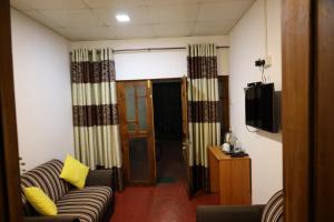 a living room with a couch and a television at Max Safari Villa in Udawalawe