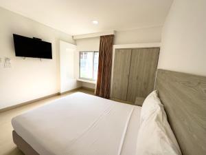 1 dormitorio con 1 cama blanca y TV de pantalla plana en Hotel Zamay Plus, en Santa Marta