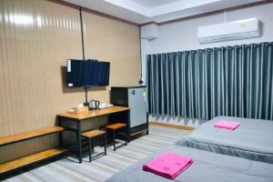 a room with two beds and a desk with a television at Pingpong Place in Ban Non Kum