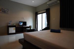 una camera con un grande letto e una televisione di Green Leaf Hostel a Phuket