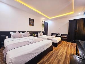 a hotel room with two beds and a tv at Win Homestay Hoi An in Hoi An