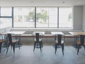 una sala da pranzo con tavoli, sedie e una grande finestra di Miyako Daiichi Hotel a Miyakojima