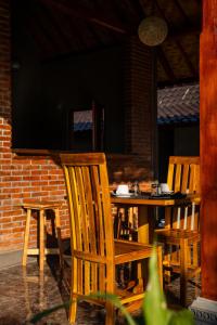 two wooden chairs and a table in front of a brick wall at The babakan accommodations in Sidemen