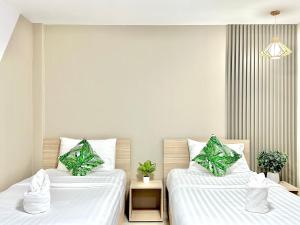 2 camas en una habitación con sábanas blancas y plantas en The Nine Place แจ้งสนิท en Ban Nong Bua