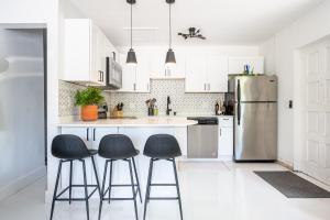 a kitchen with a refrigerator and three bar stools at Lighthouse Guest Suites in Fort Lauderdale